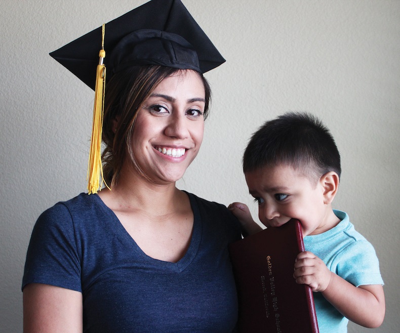 Mother wearing a graduation cap holding her child